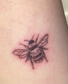 a small tattoo of a bee on the back of a woman's thigh,