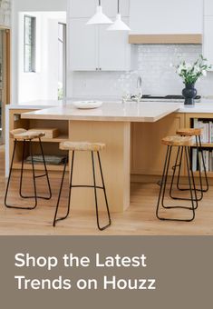 a kitchen with white cabinets and stools next to an island in the middle of it