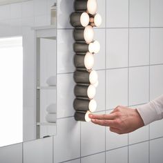 a person is holding something in front of a mirror with lights hanging from it's sides