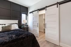 a bedroom with black and white bedding, two sliding barn doors and a nightstand