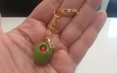 a hand holding a green keychain with a red bead on it