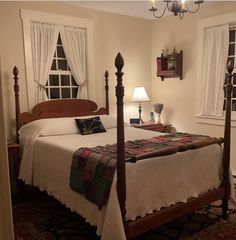 a bed sitting in a bedroom next to two windows