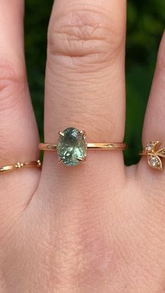 a woman's hand with two rings on it and an aqua green stone in the middle