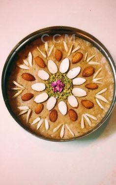 a metal bowl filled with almonds and other nuts on top of a white table