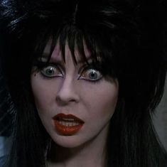 a woman with long black hair and red lipstick on her face, wearing cat makeup