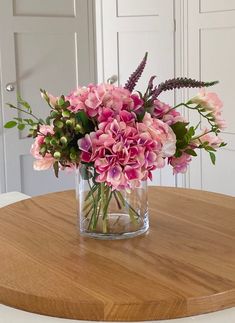 a vase filled with pink flowers on top of a wooden table