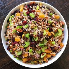 a white bowl filled with rice, dried fruit and nuts on top of a wooden table