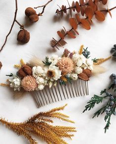 dried flowers and leaves are arranged on a white surface next to a comb of hair