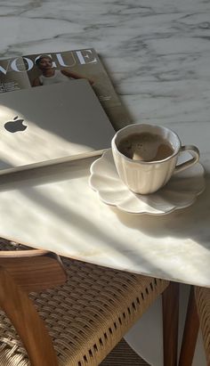 a cup of coffee sitting on top of a table next to an apple computer book