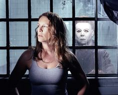 a woman standing in front of a window with two creepy faces on the windowsill