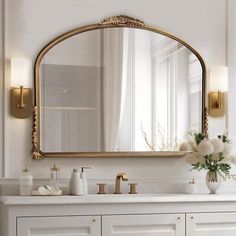 a bathroom vanity with a large mirror above it and flowers in a vase on the counter