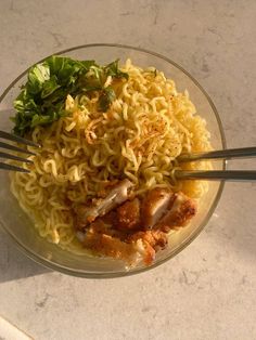 a bowl filled with noodles and meat on top of a white marble counter next to chopsticks