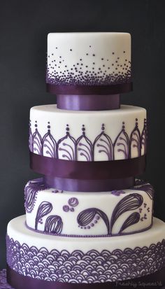 a three tiered cake with purple decorations on it