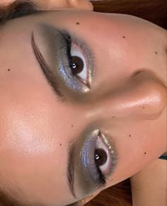 a woman with blue and silver makeup looks at the camera while laying on her side