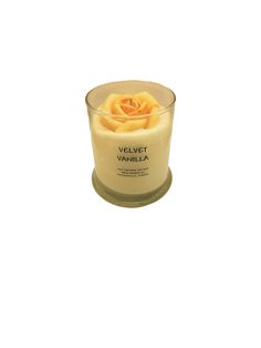 a candle that is sitting on top of a white surface with a yellow rose in it