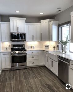 a large kitchen with white cabinets and stainless steel stove top oven, dishwasher, microwave and sink