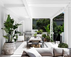 an outdoor living area with couches, tables and potted plants