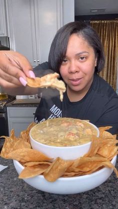 a woman eating a bowl of soup with tortilla chips