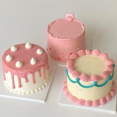 three cakes are sitting on top of each other, one is pink and the other is white