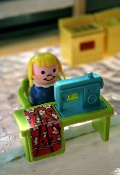 a toy sewing machine sitting on top of a table next to a small child's doll