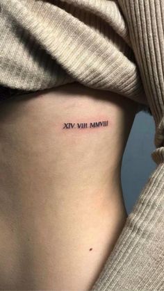 a woman's stomach with the words roman numeral tattoo on her left side