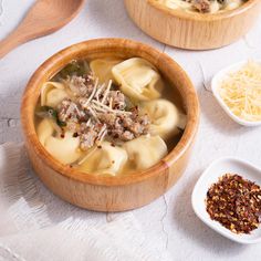 two wooden bowls filled with pasta and meat soup