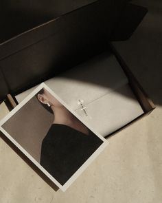 an open box on the floor with a photo inside it and a piece of paper in front of it