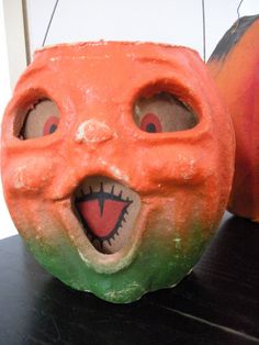 an orange and green pumpkin with a face painted on it's side sitting next to another one