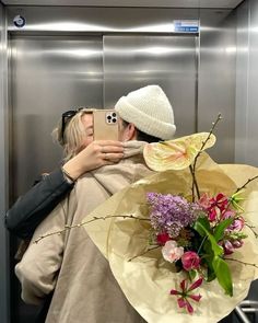 a woman taking a selfie with her cell phone while holding a bouquet of flowers