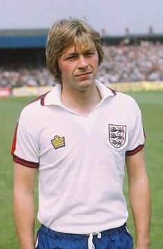 a man standing on top of a soccer field wearing a white shirt and blue shorts