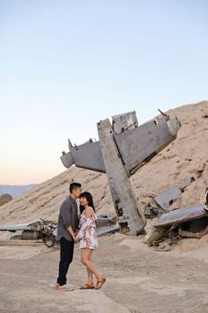 a man and woman standing in front of an airplane wreck