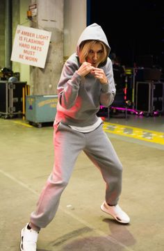 a woman in grey hoodie and pink sweatpants dancing