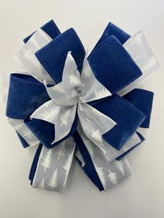 a blue and white christmas bow with trees on it's side, sitting on top of a table