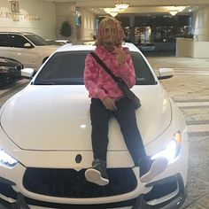 a woman sitting on the hood of a white car