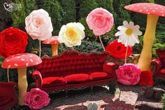 a red couch sitting next to flowers and mushrooms