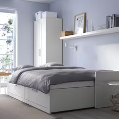 a white bed sitting next to a window in a bedroom