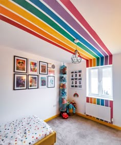 a bedroom with rainbow painted on the ceiling and pictures hanging above the bed in front of it