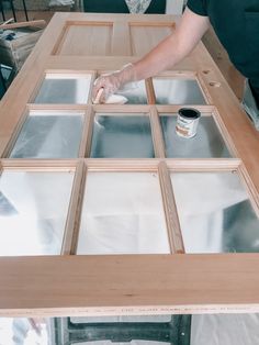 a person painting glass on top of a wooden table