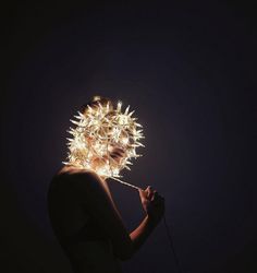 a woman with lights on her head is holding a string in front of her face