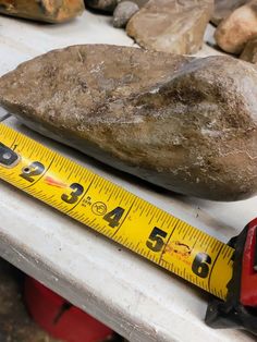 a large rock sitting on top of a table next to a measuring tape