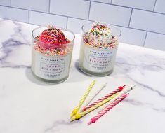 two candles are sitting next to each other on a marble counter with sprinkles