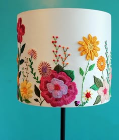 a lamp with flowers painted on it sitting next to a blue wall and green background