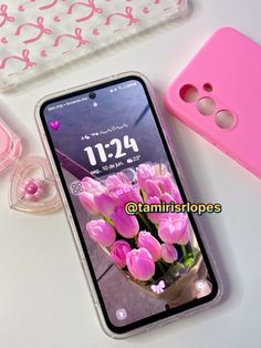 a pink phone case sitting on top of a white table next to some pink flowers