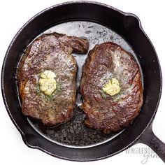 two steaks in a cast iron skillet with butter on the top and mustard on the bottom