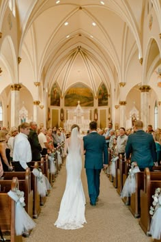 a bride and groom walking down the aisle at their wedding ceremony in a church with pews