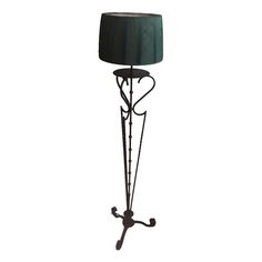 an iron floor lamp with a green shade