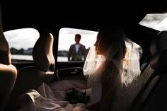 a bride and groom sitting in the back seat of a car