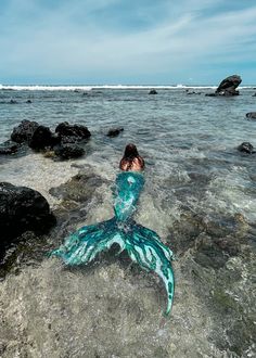 a woman laying on top of a rock in the ocean next to an octopus tail