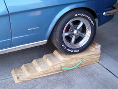 a blue car parked next to a wooden platform with a tire on it's side