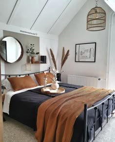 a bed sitting in a bedroom next to a wall mounted mirror and a wooden table